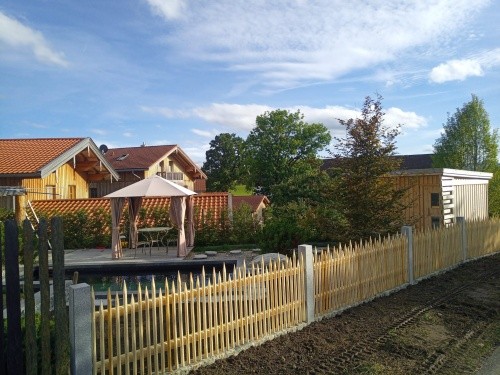 Holzzaun mit Natursteinelementen als Grundstücksabgrenzung