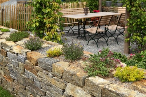 Naturstein-Gartenmauer mit Bepflanzung als Abgrenzung im Garten