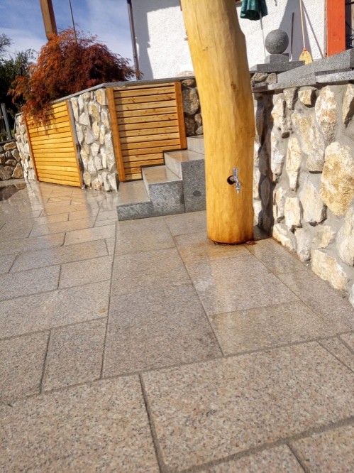 Natursteinterrasse mit Gartenmauer aus Holz- und Steinelementen